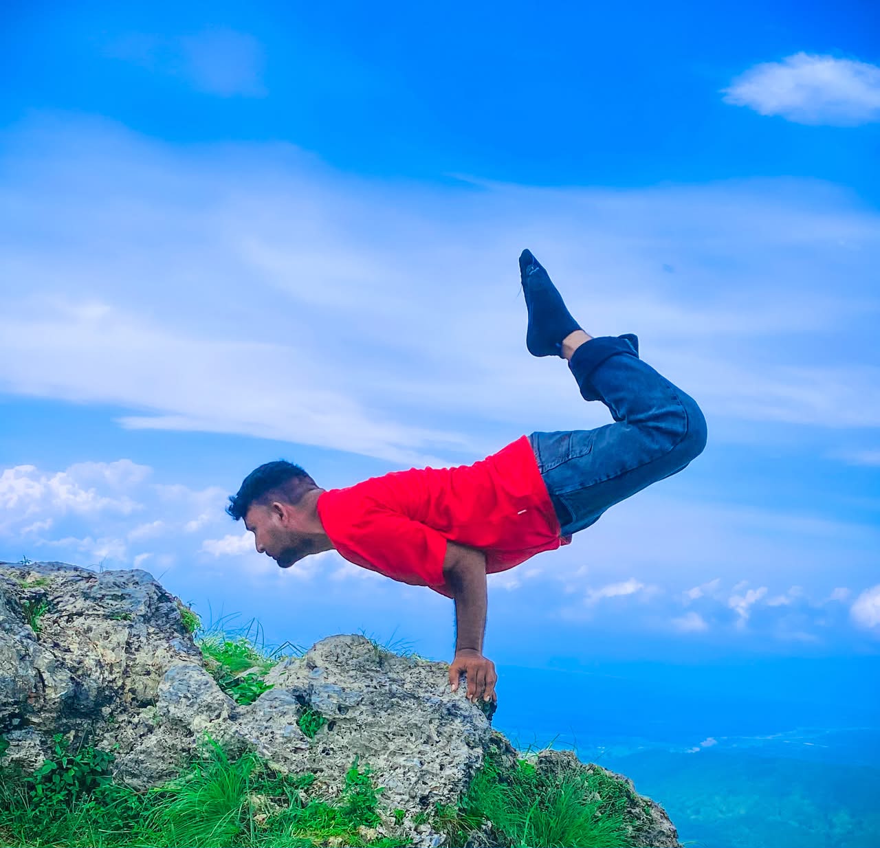 Advanced yoga arm-balance pose on a cliff at Ved Yoga Shala