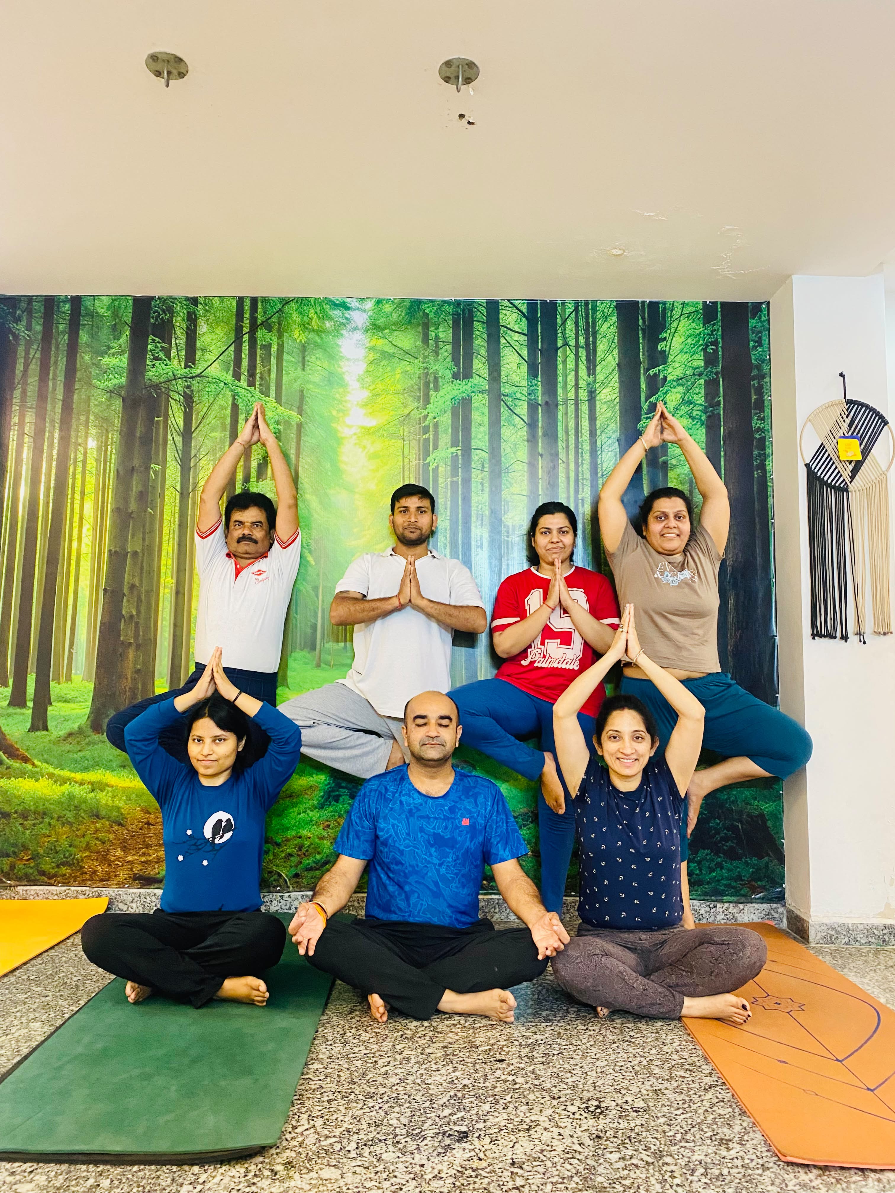 Group meditation and asana class in front of the forest mural at Ved Yoga Shala